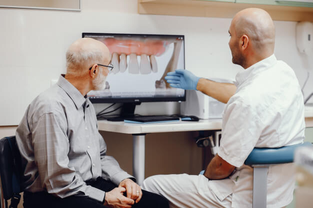 dentista e paciente verificando o mini implante no computador