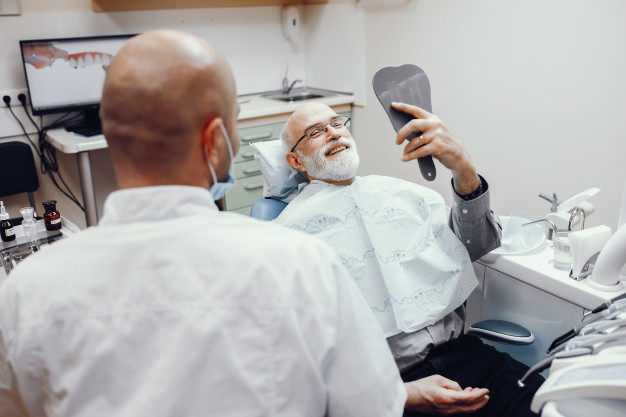 mini implante homem no consultório olhando para um espelho e sorrindo