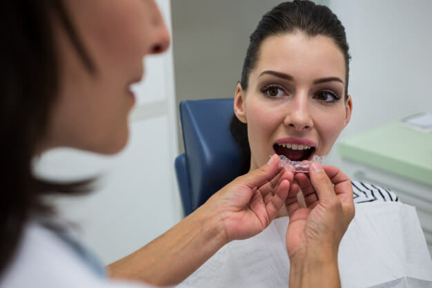 tipos de aparelho mulher com boca aberta e dentista segurando aparelho