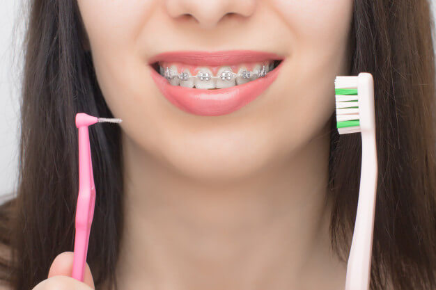 mulher mostrando escovas de dente elástico ortodôntico