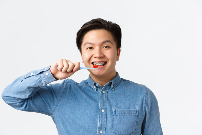 como escovar os dentes com aparelho homem escovando dentes